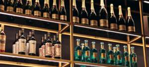 A modern bar shelf illuminated by wine bottles.