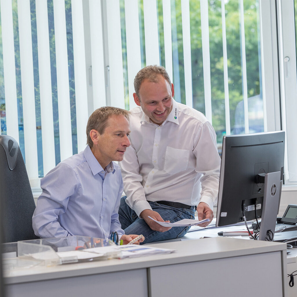 Two people are working together at a computer to discuss and develop an innovative industrial solution.