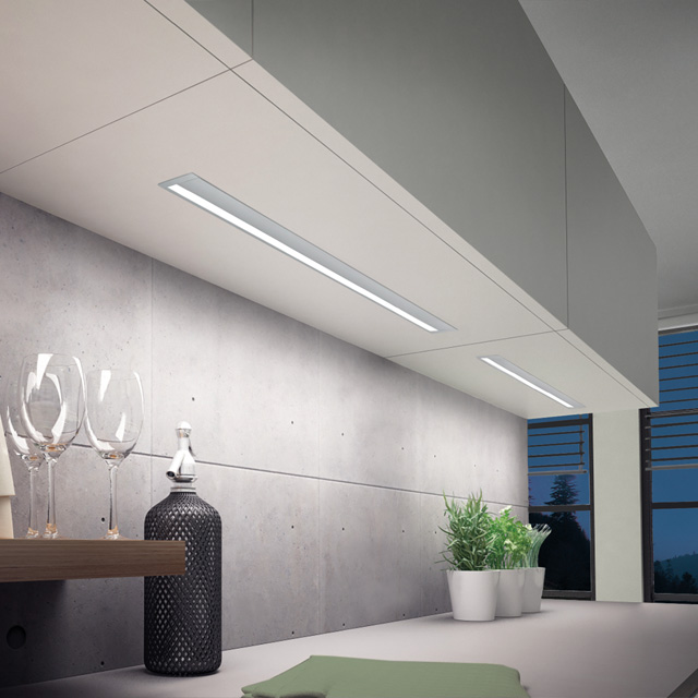 An elegant grey kitchen with indirect lighting, stylish glassware and modern accents on the worktop.