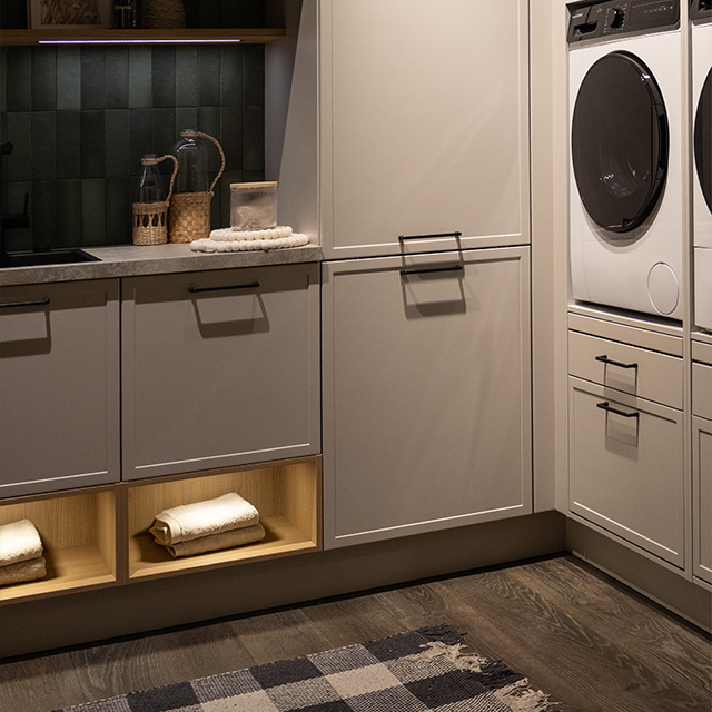 A modern laundry room with stylish cupboards, a washing machine and warm lighting that creates a welcoming atmosphere.
