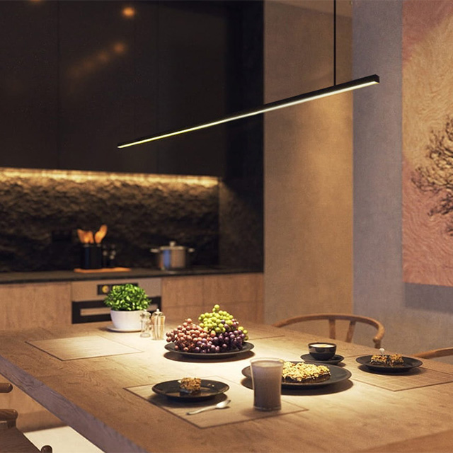 A modern dining area with elegant lighting, fresh fruit and a laid table, perfect for social gatherings