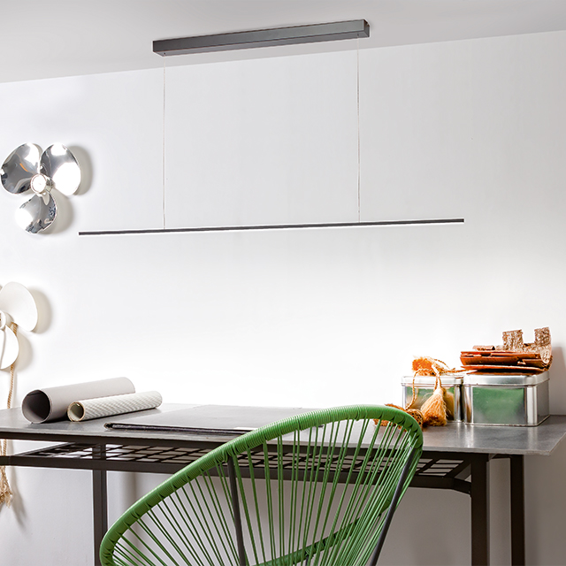 A stylish workspace featuring a minimalist LED lamp and a modern green chair creates a pleasant atmosphere.