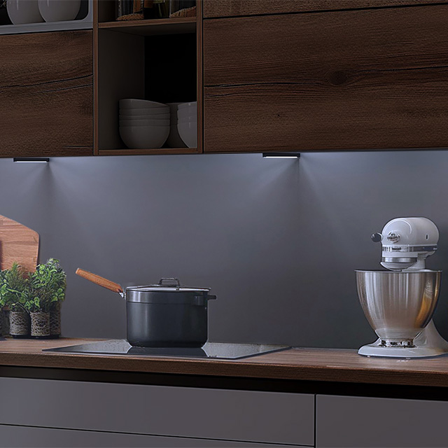 Dark kitchen with an illuminated worktop featuring a hob and a food processor