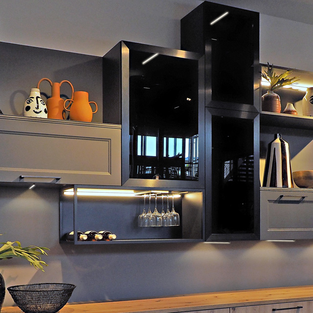 Illuminated wall unit with dark grey fronts and glass panels