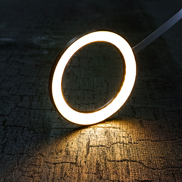 A circular LED light ring casts a warm glow onto a textured wooden surface, creating a pleasant atmosphere.